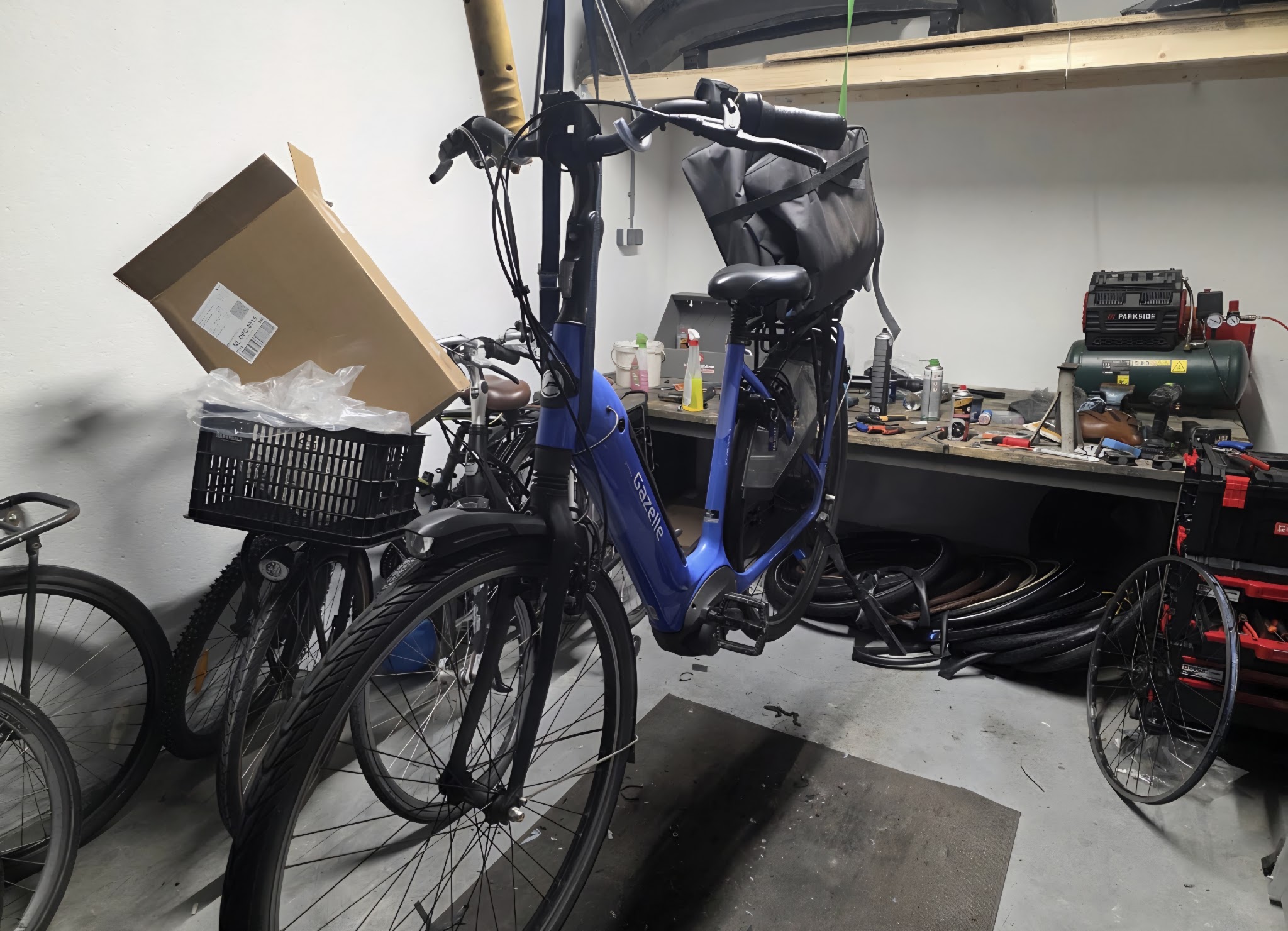 De werkplaats met werkbank, gereedschap, compressor en een e-bike in onderhoud