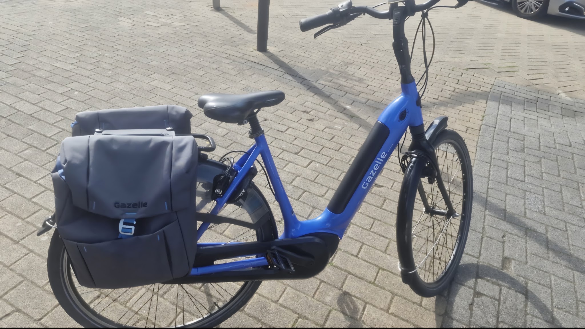 Een blauwe Gazelle e-bike met fietstassen, na onderhoud weer rijklaar